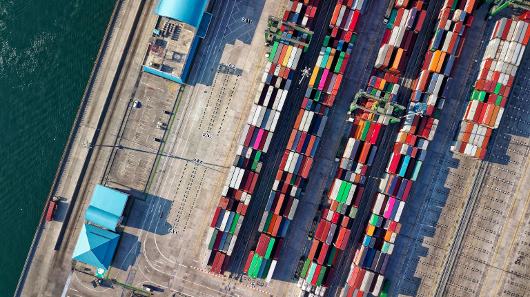 Photo of an aerial view of colorful shipping containers at a port terminal.