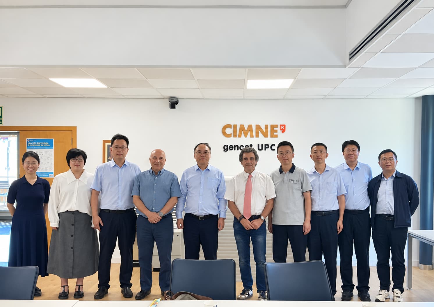 Group photo of the Chinese delegation with CIMNE representatives in the Olgierd Cecil Zienkiewicz (OCZ) Conference Room at CIMNE’s headquarters in Barcelona. Dr Gabriel Bugeda, fourth from left, and Dr Sebastià Olivella, fifth from right, stand with the delegation in front of the CIMNE and gencat–UPC signage.