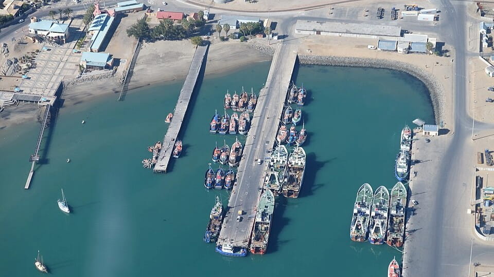 Aerial bird's-eye view of the coastal shipping port and harbor infrastructure in Lüderitz, Namibia.